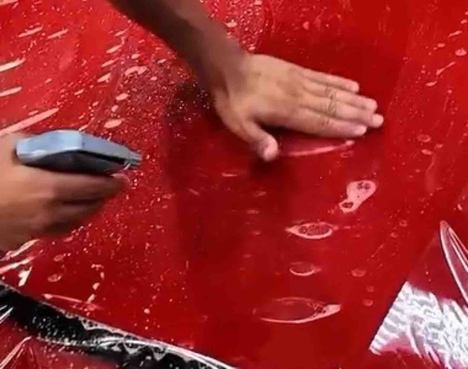 Installer squeegeeing clear paint protection film on a Ferrari 458 hood